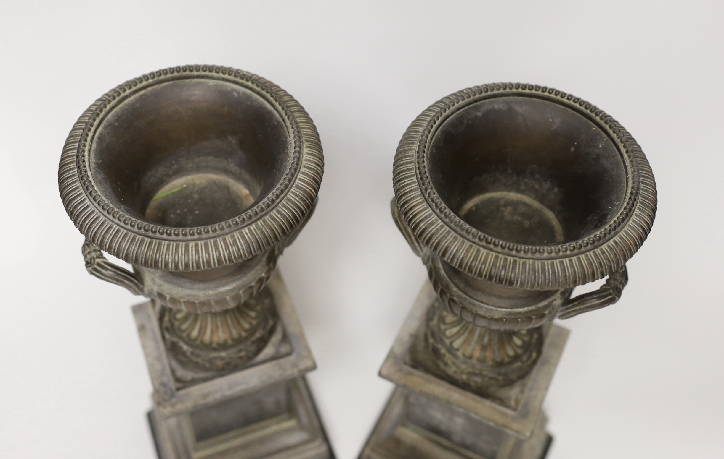 A pair of late 19th century bronze campana urns on rectangular pedestals, each 32cm high